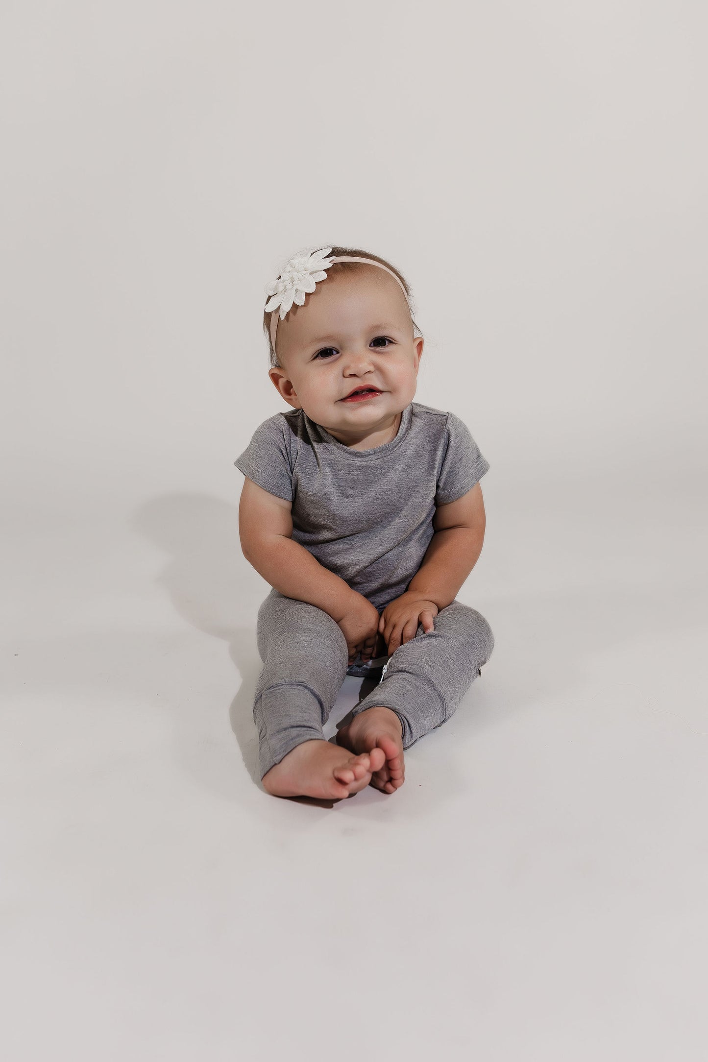 Little girl sitting on the floor wearing a grey Bamboo Lyocell Zipease Romper