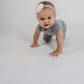 Little girl crawling toward the camera wearing a grey Bamboo Lyocell Zipease Romper