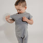 Little boy pulling on his stretchy neckband wearing a grey Bamboo Lyocell Zipease Romper