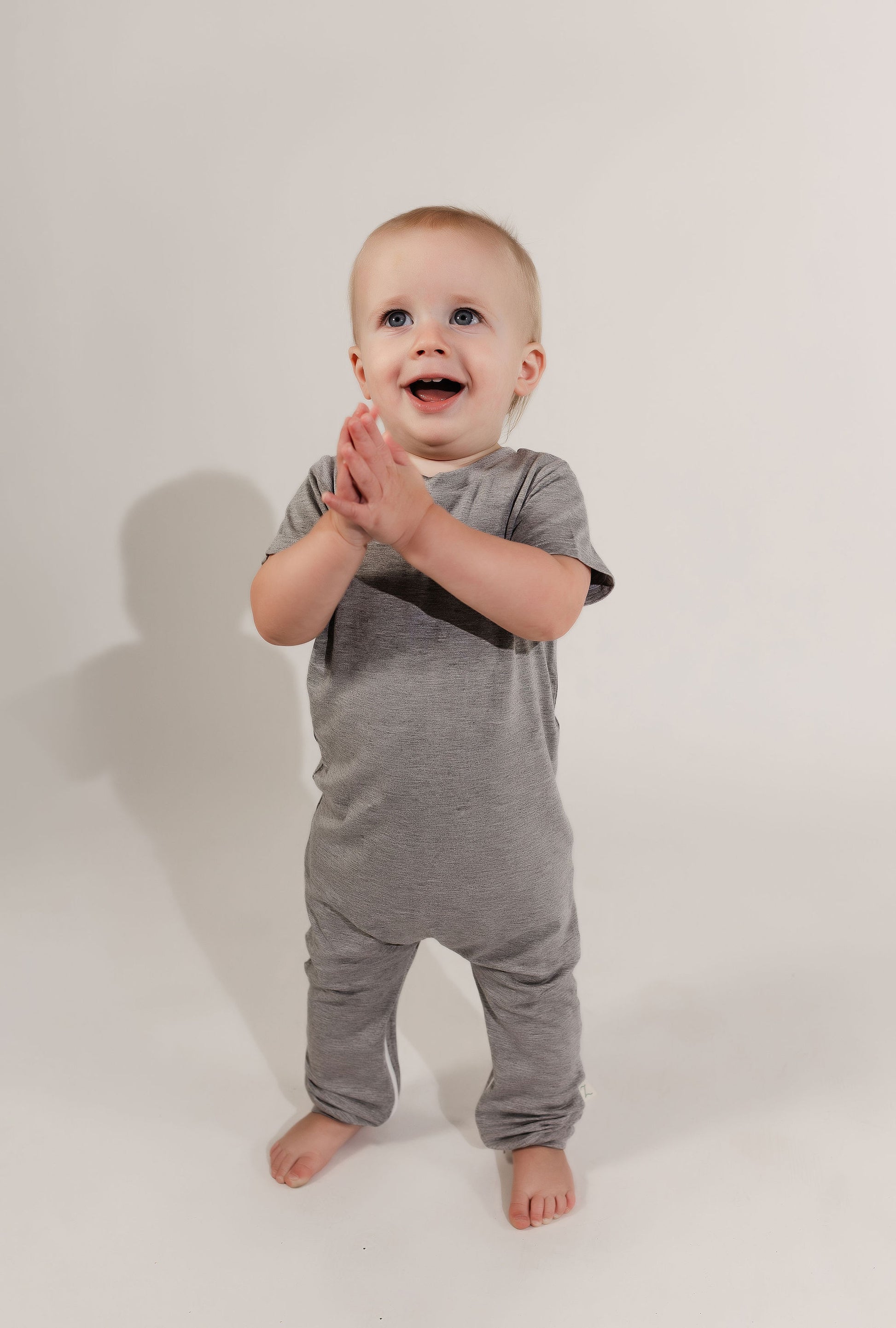 Little boy walking around clapping wearing a grey Bamboo Lyocell Zipease Romper