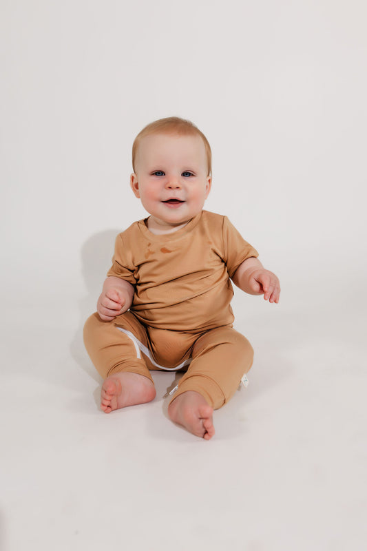 Little boy smiling wearing a camel tan Bamboo Lyocell Zipease Romper