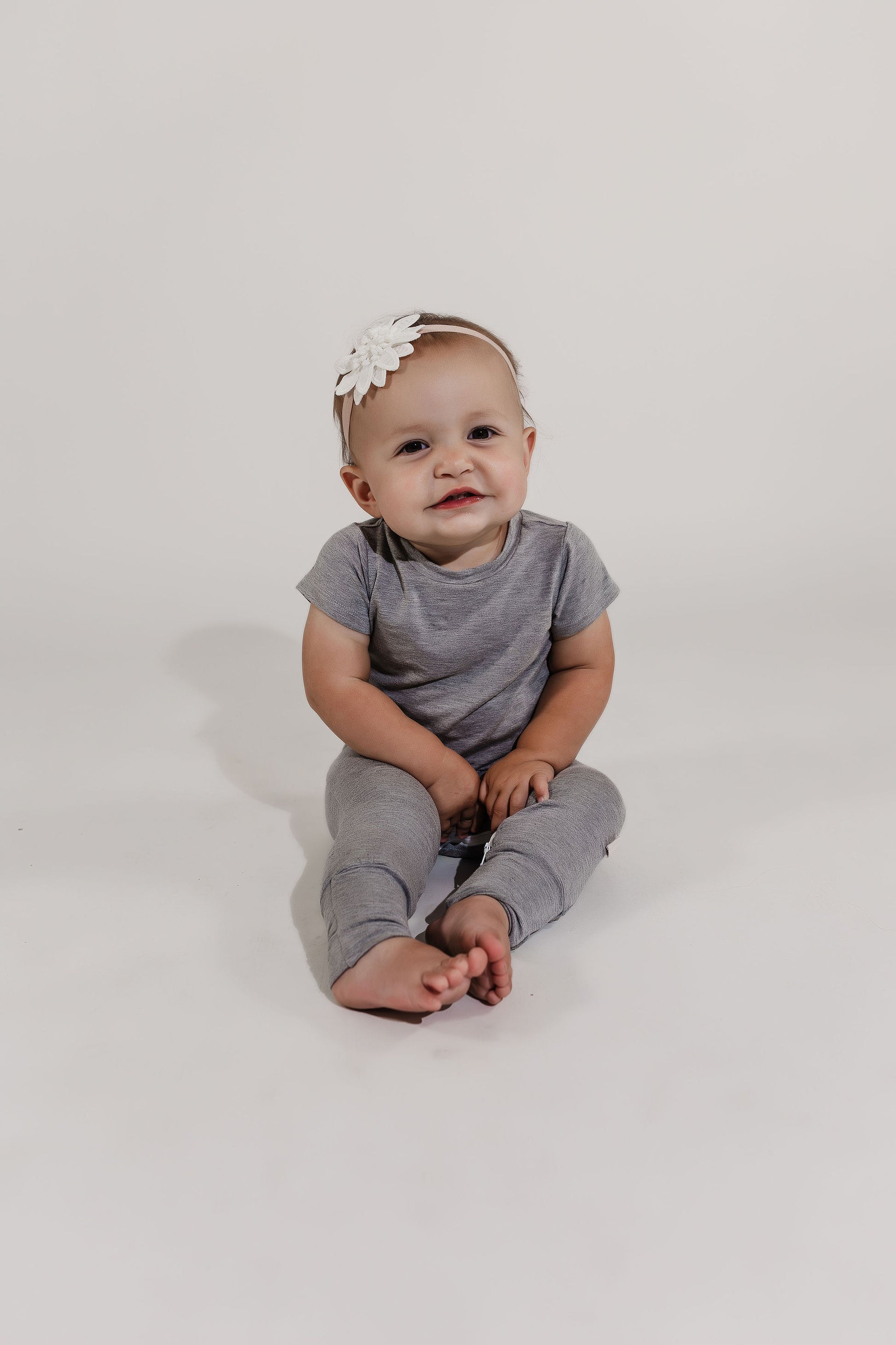 Little girl sitting on the floor wearing a grey Bamboo Lyocell Zipease Romper